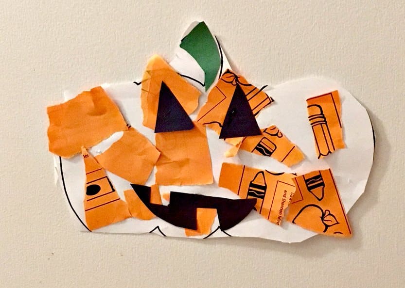 A white paper pumpkin with torn pieces of orange, green, and black paper to create a jack o lantern.