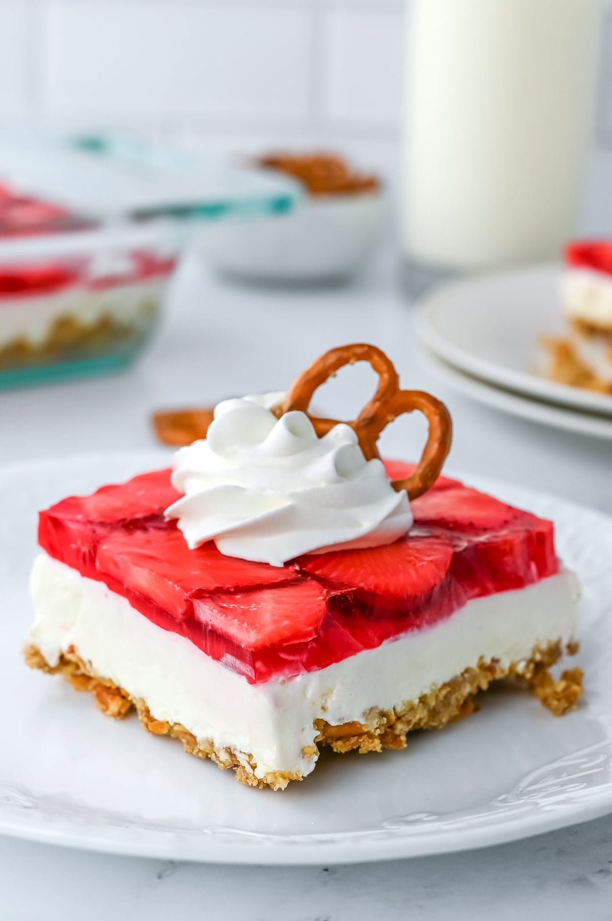 Strawberry pretzel salad bar on a plate with whipped cream and pretzels, creating a delightful strawberry pretzel salad dessert.