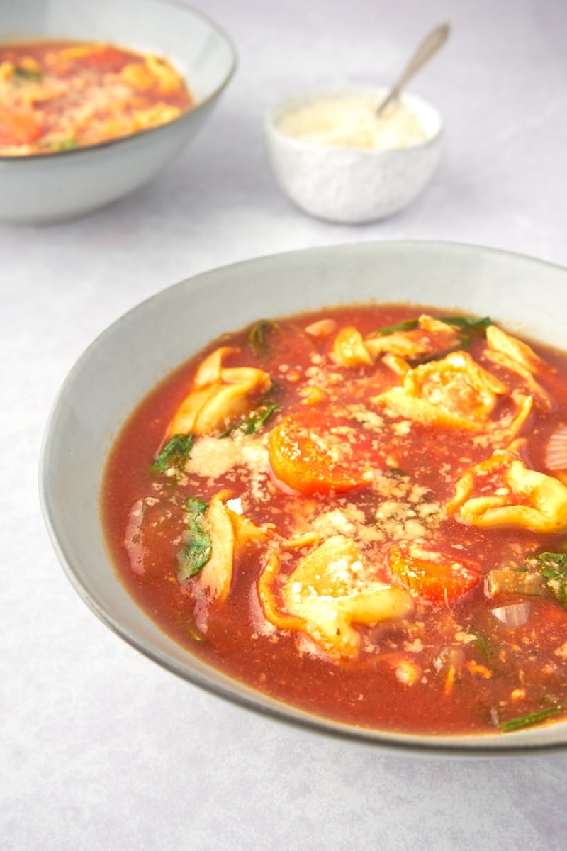 tomato tortellini soup with chicken and spinach in a bowl with parmesan on top