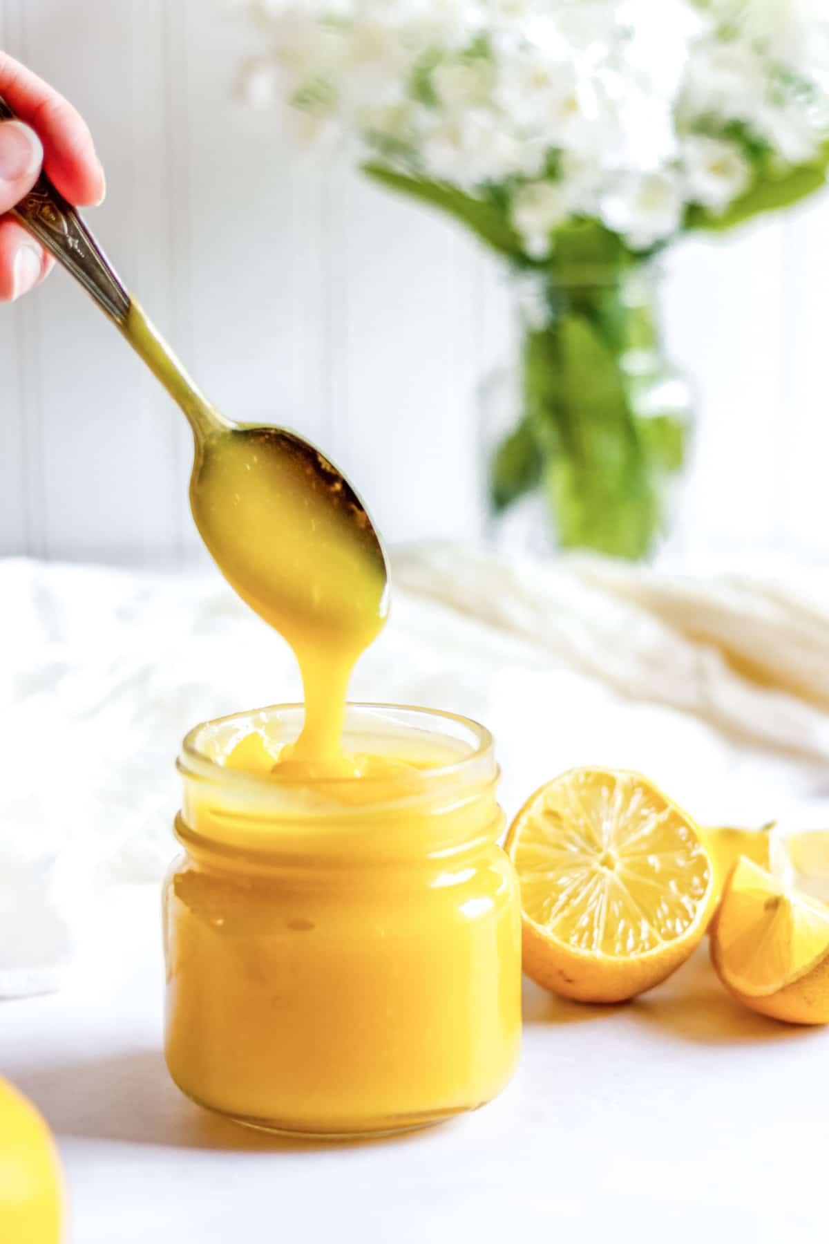 lemon curd in a jar with a spoon dripping