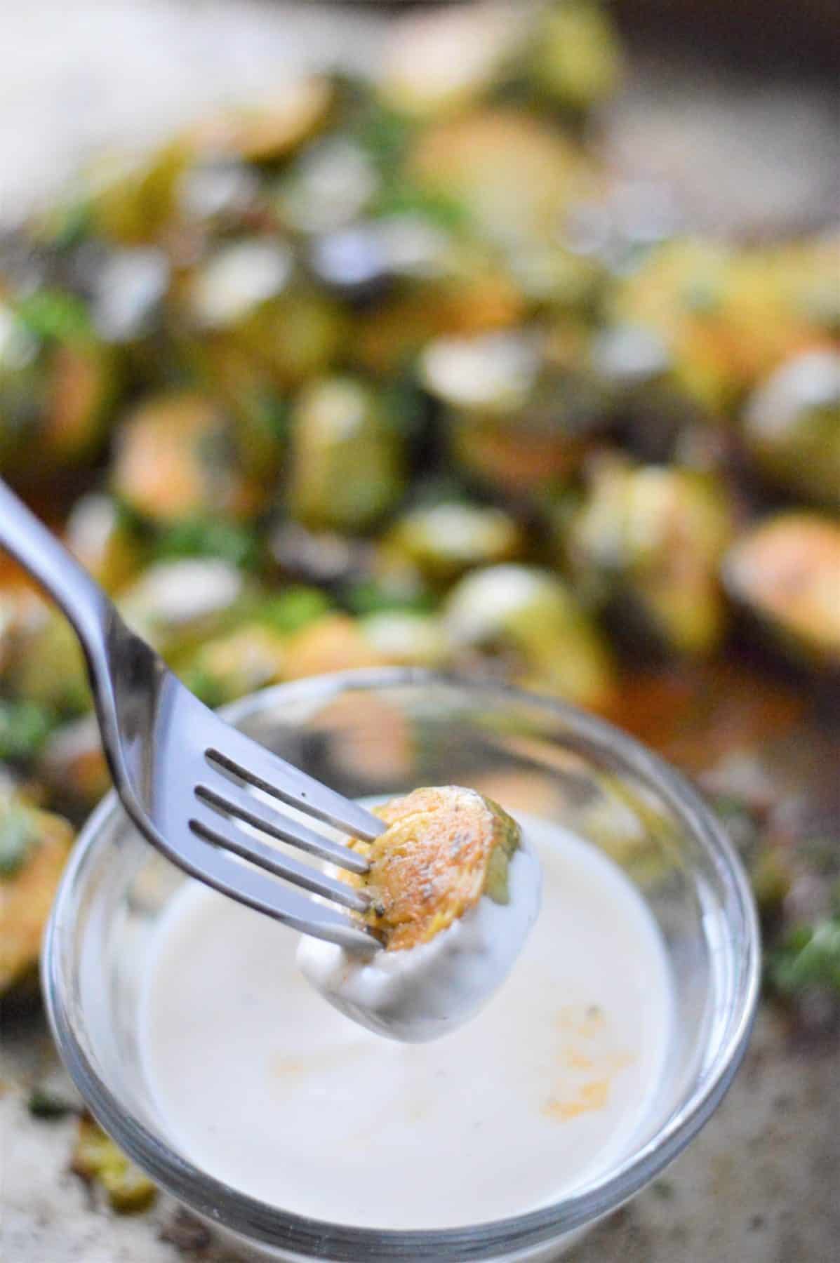 Buffalo Ranch Brussel Sprouts on fork dipped in ranch dressing