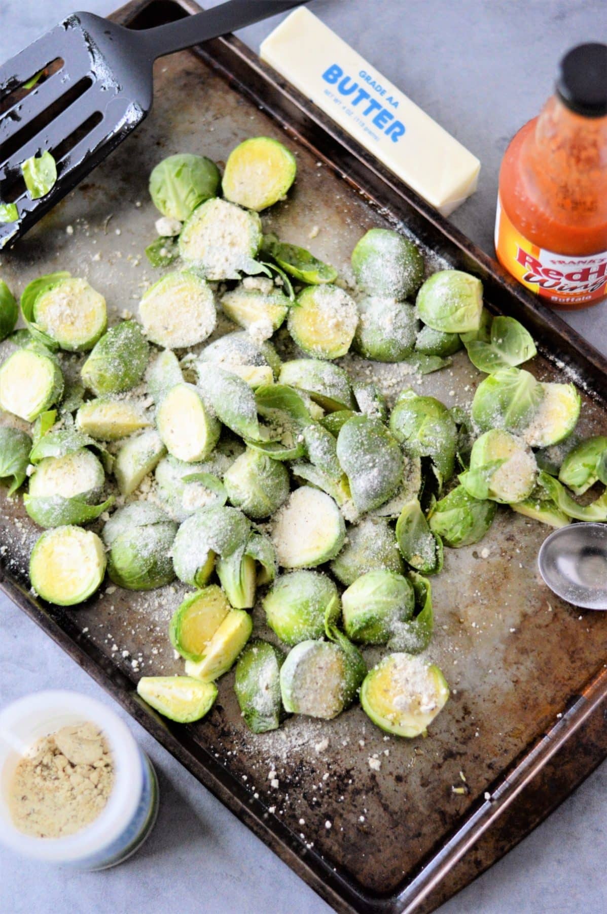 Raw brussels sprouts on a baking sheet with oil and seasoning sprinkled on