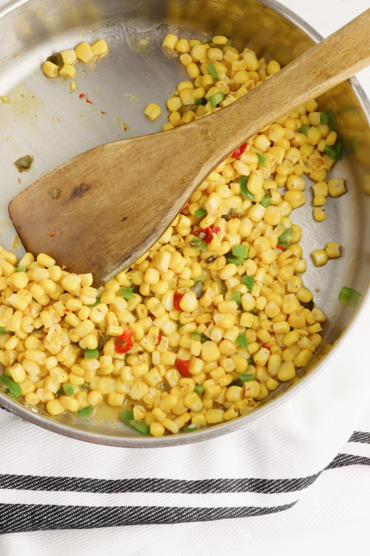 saute southwest corn and jalapenos in skillet with wooden spoon
