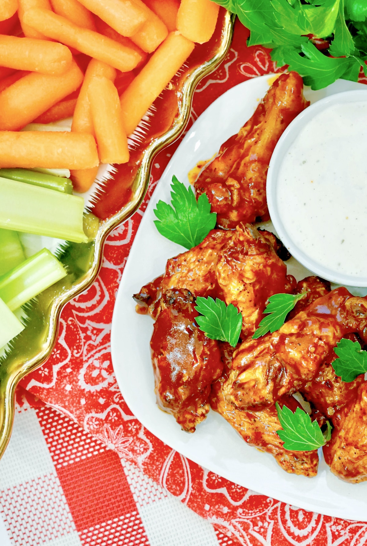 hot wings on a plate with carrots and celery on another plate and a bowl of dipping sauce
