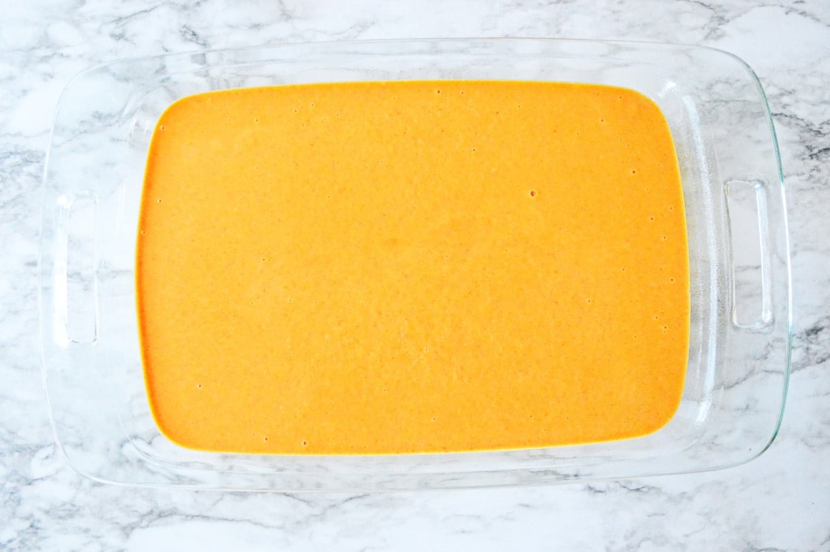 pumpkin layer spread on top of cake batter in glass baking pan