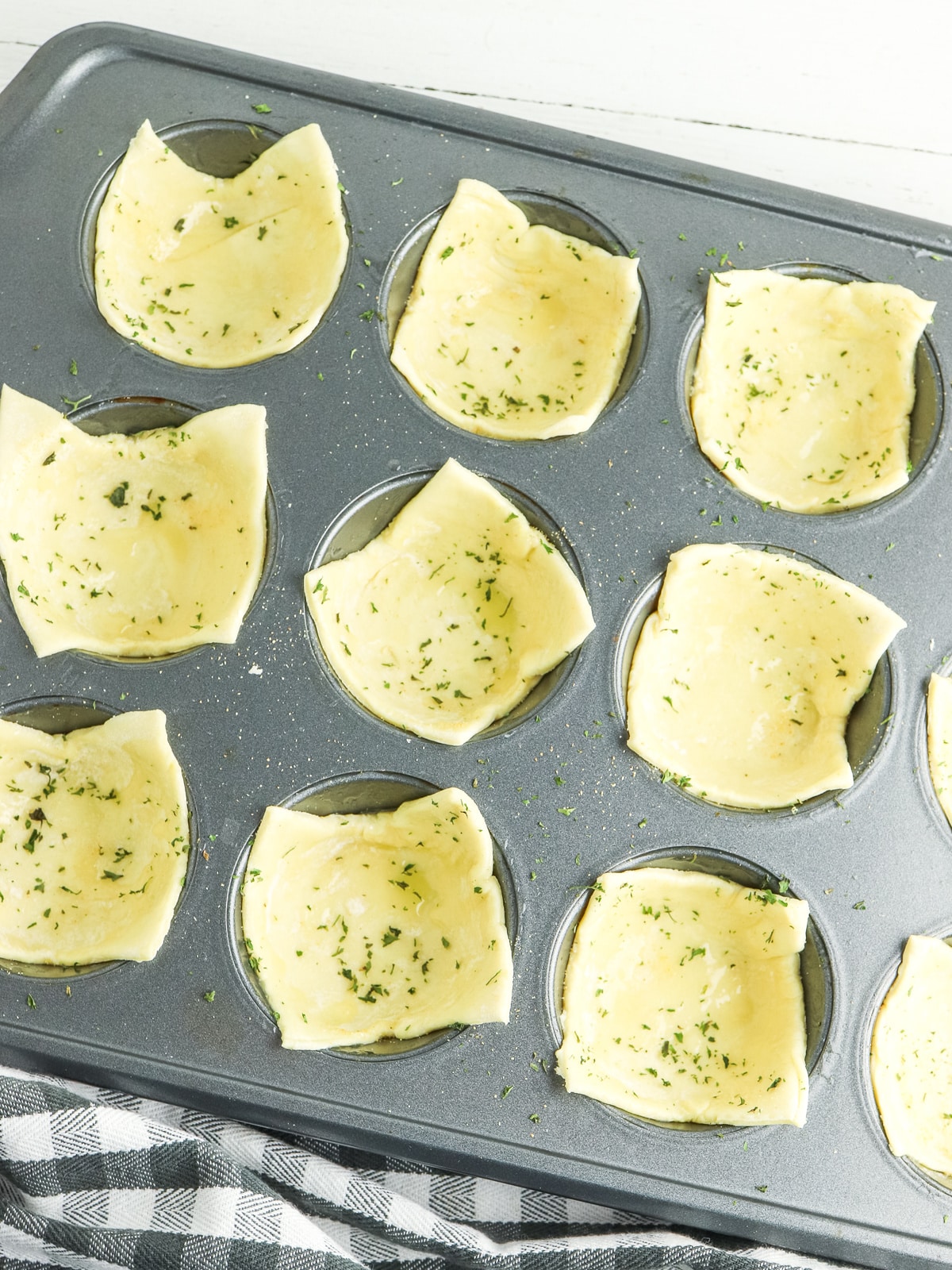 add pastry pieces to muffin tin with butter