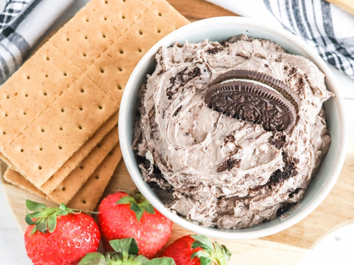 creamy oreo cheesecake dip in a bowl with strawberries and graham crackers on the side