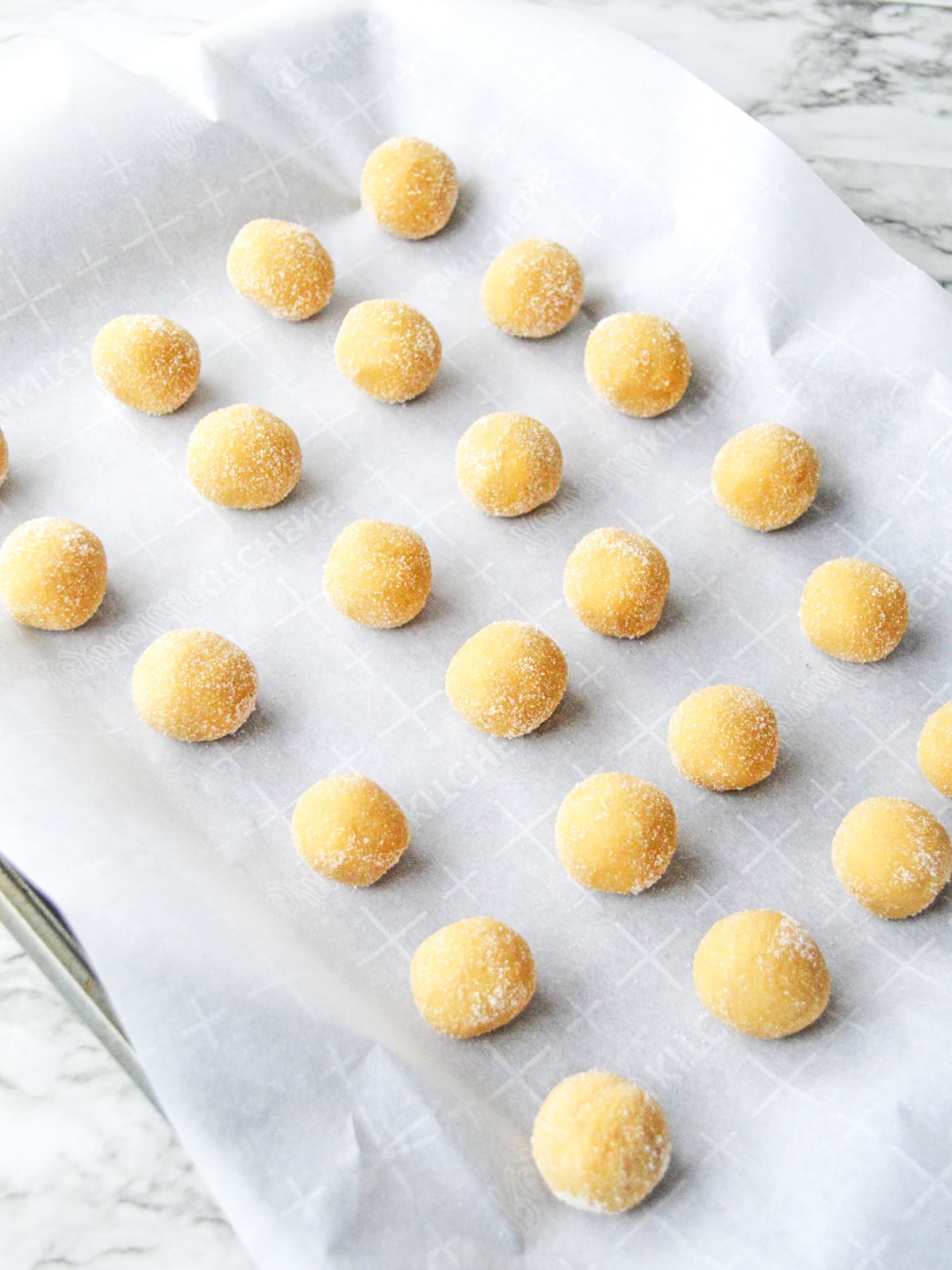 place rolled cookie balls on parchment paper lined cookie sheet