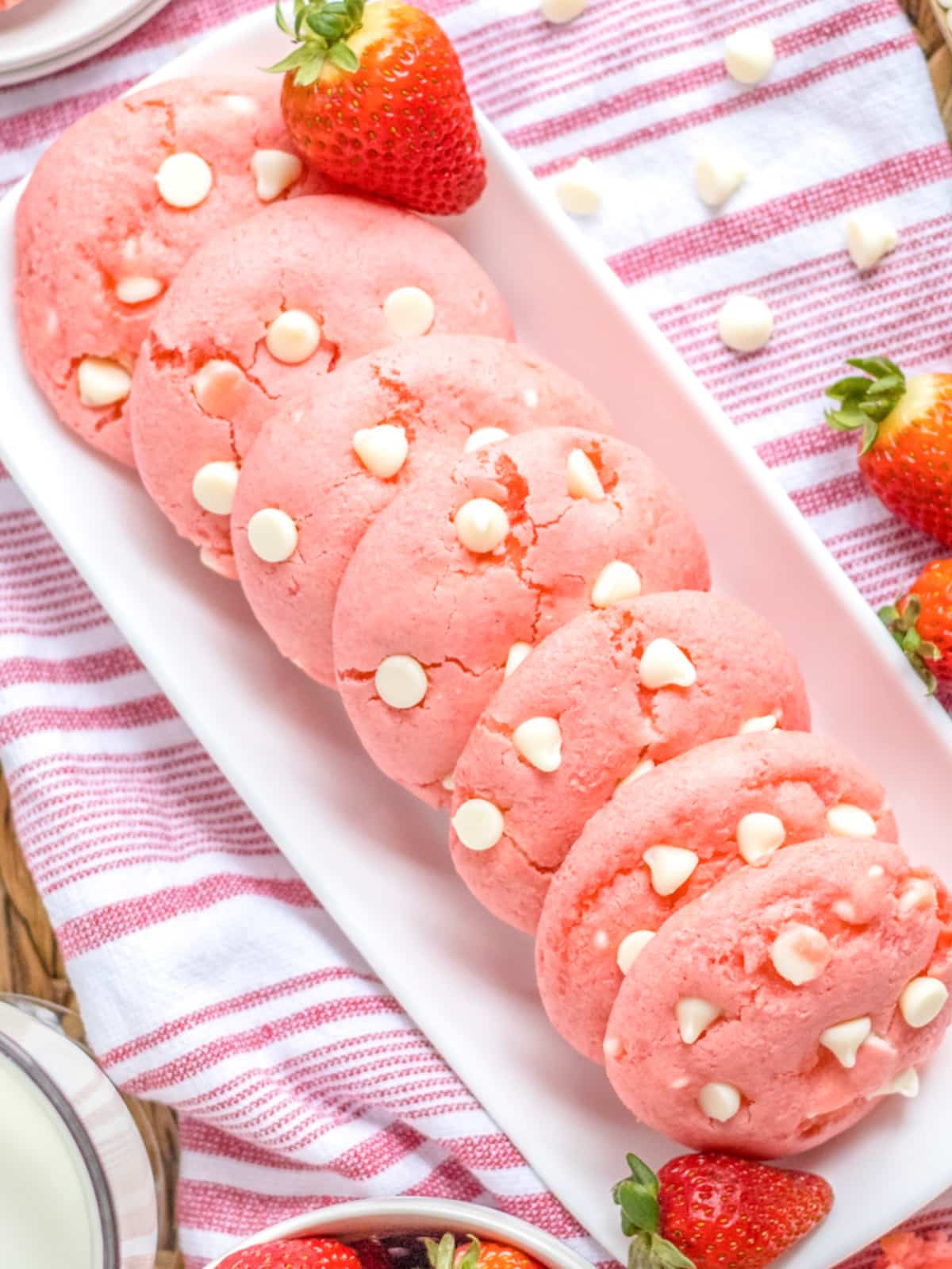 Strawberry cheesecake cookies arranged on a rectangular plate with a red and white striped towel