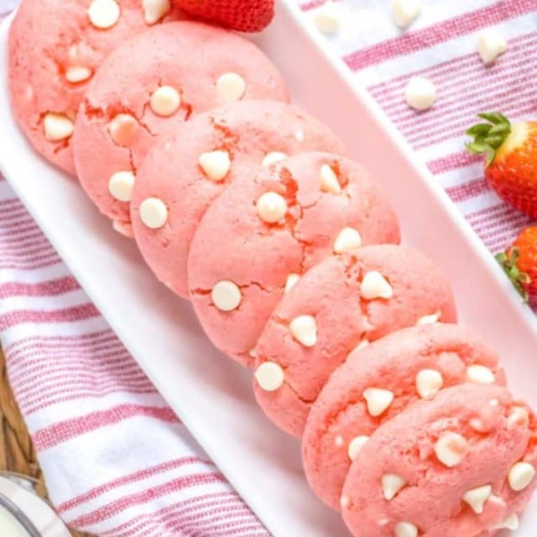 Strawberry cheesecake cookies arranged on a rectangular plate with a red and white striped towel