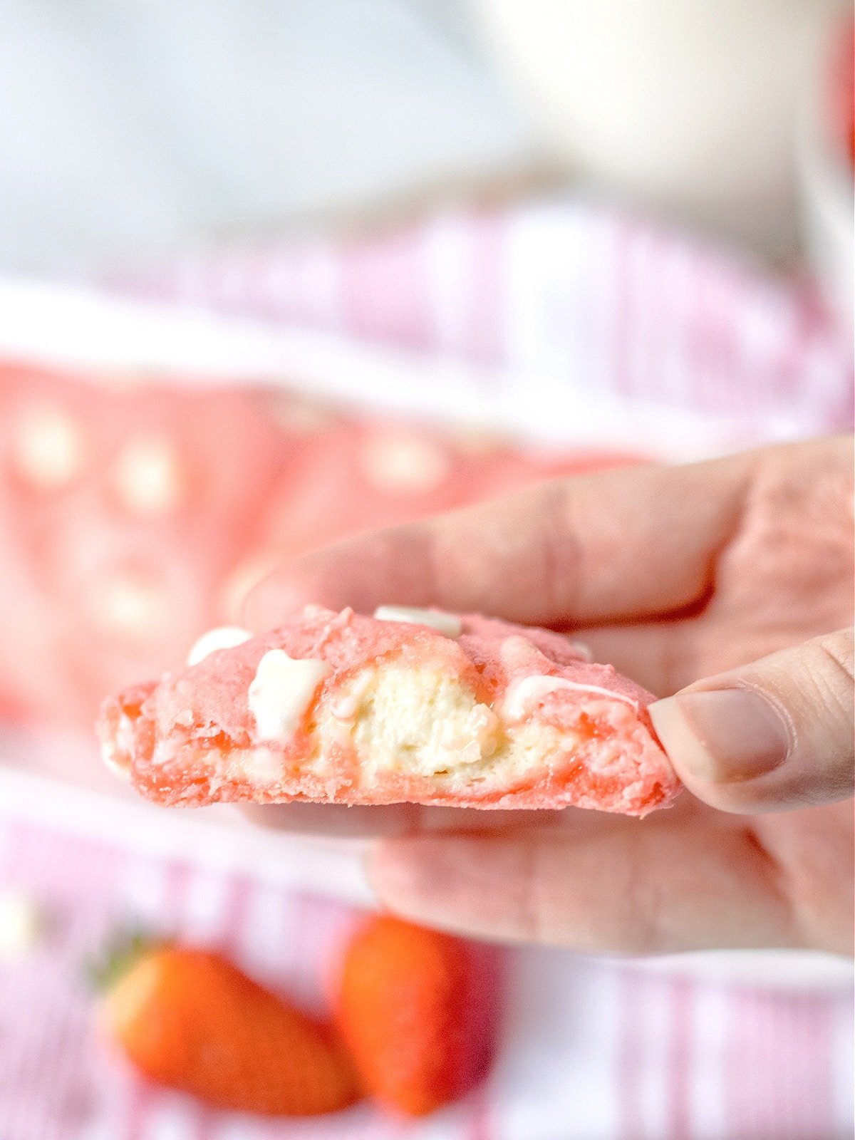 hand holding a Strawberry cheesecake cookie with bite taken