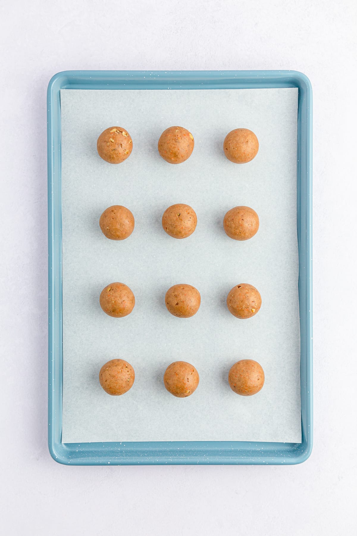 Carrot Cake dough balls on a lined cookie sheet.
