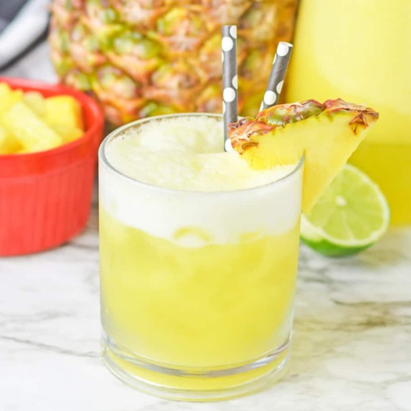 Pineapple agua fresca in a glass with straws