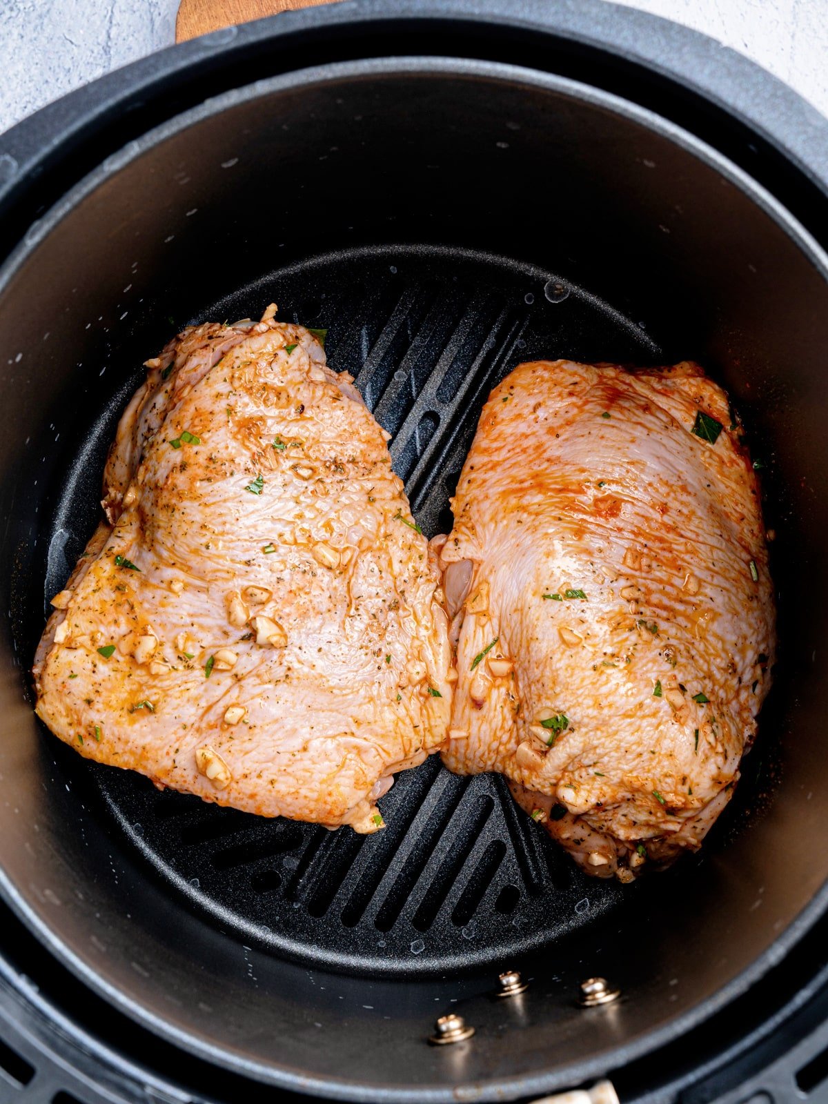 Uncooked Chicken Thighs in air fryer basket