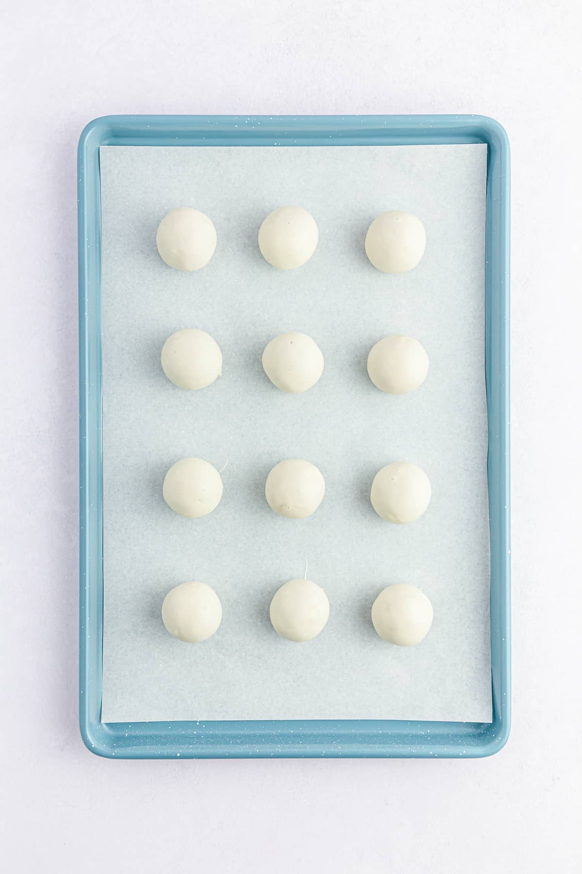 White chocolate dipped Carrot Cake Balls on cookie sheet.