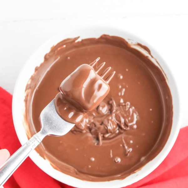 dip candy in bowl of melted chocolate with fork