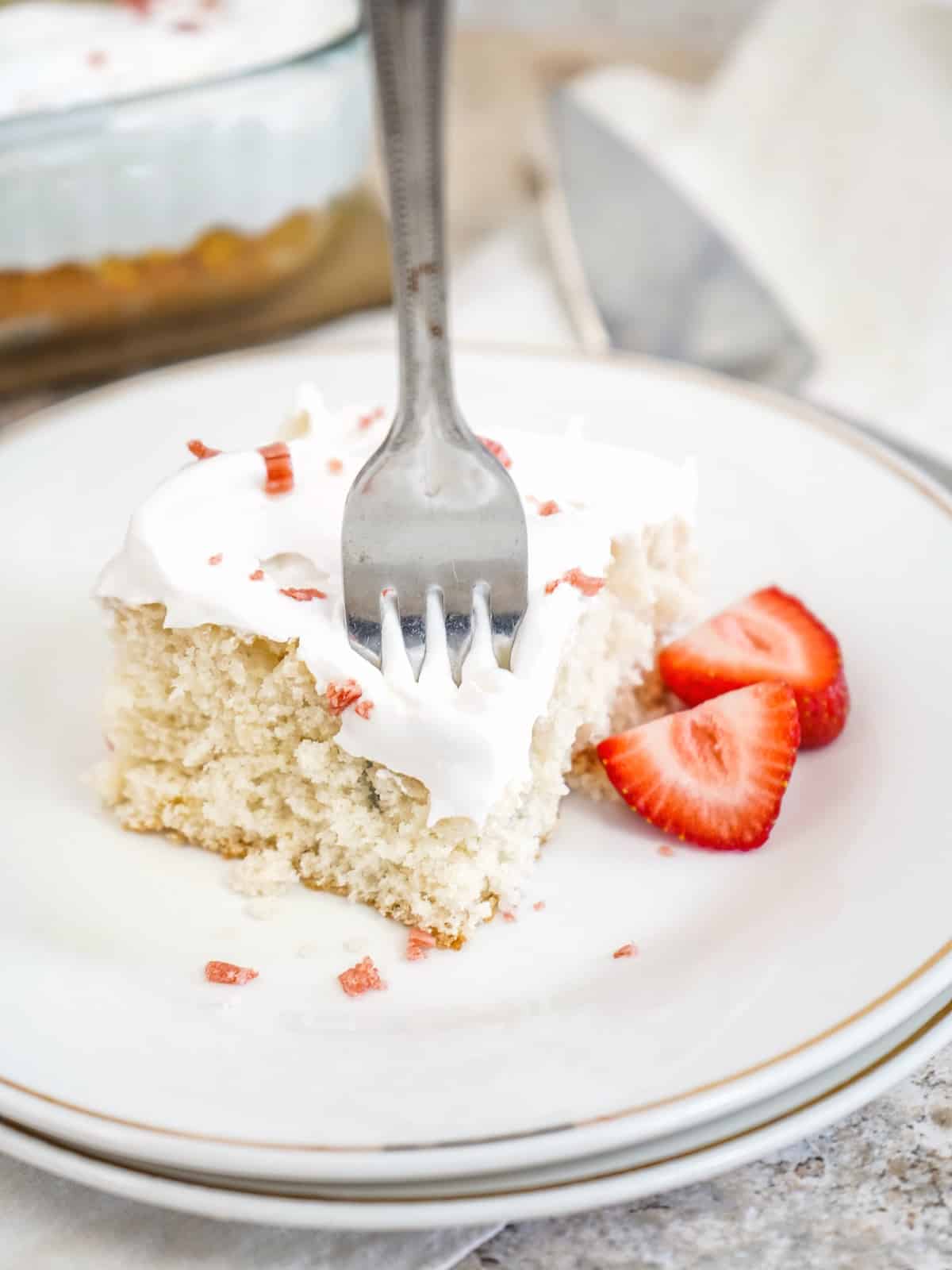 fork in cream soda cake on white plate