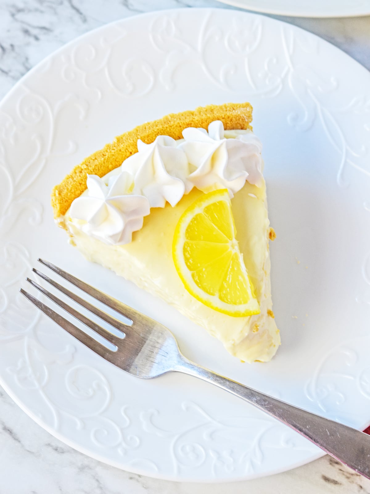 lemon pie slice on a white plate with fork