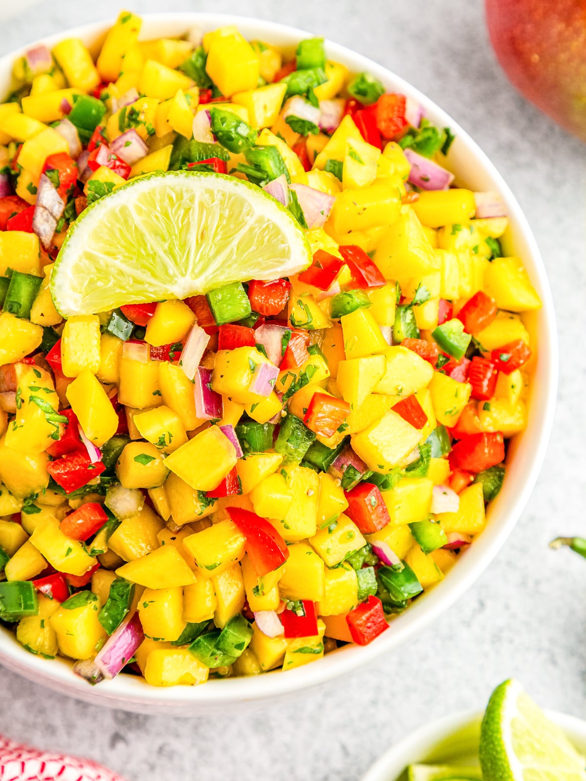 mango salsa in white bowl with lime slice