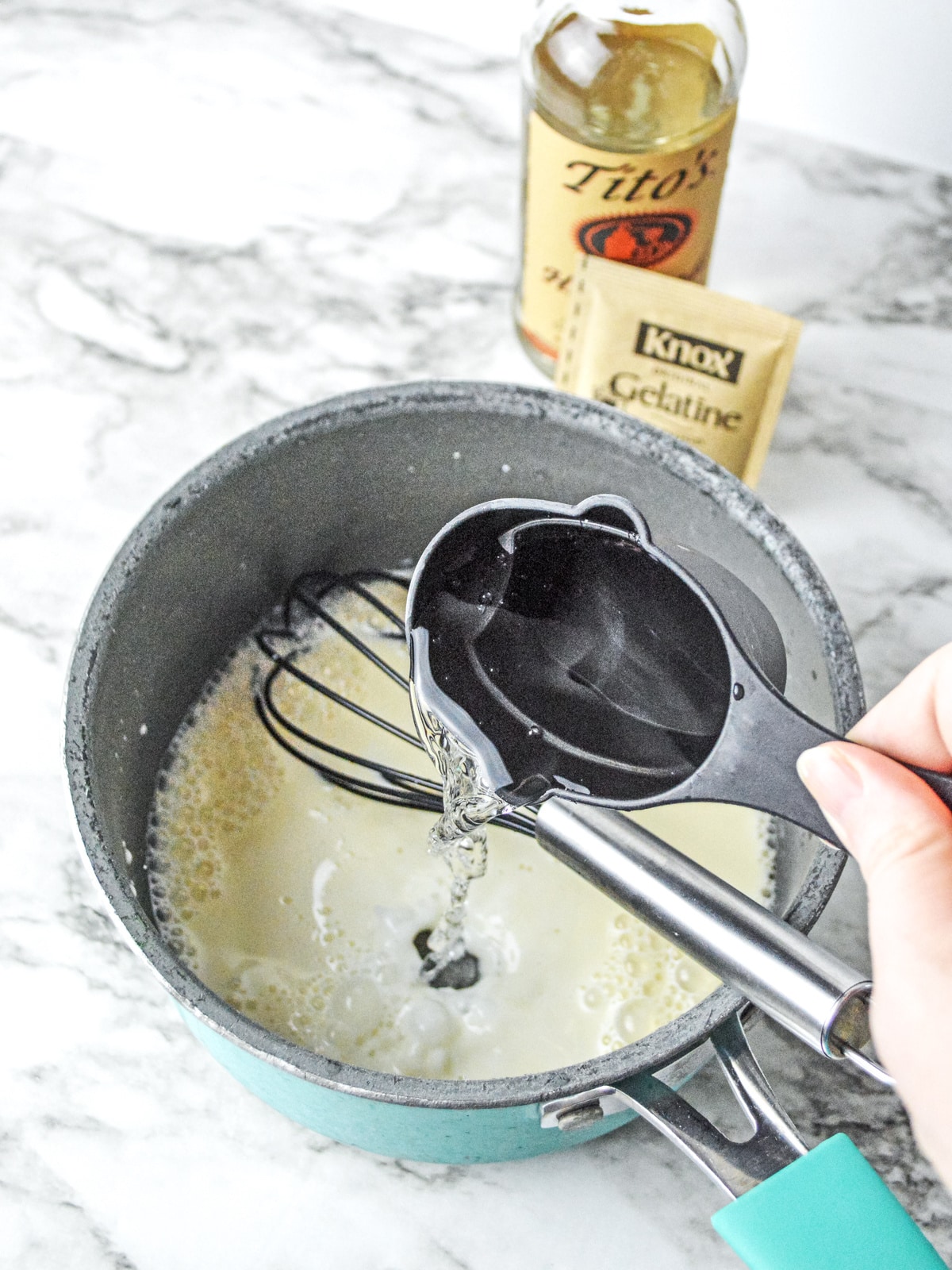 pouring vodka into gelatin with condensed milk in sauce pan