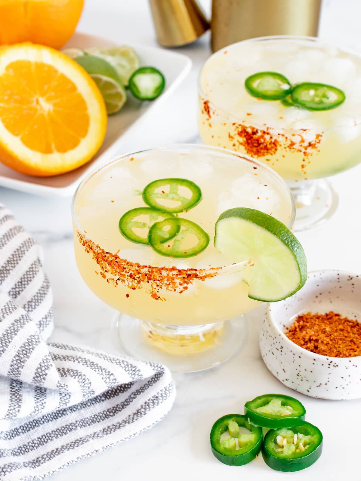 spicy margaritas in glasses with jalapeno and lime garnish
