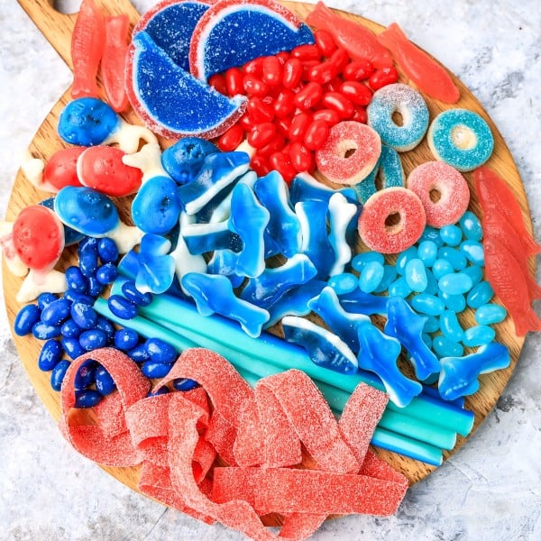 assorted red and blue candies on a wooden cutting board.