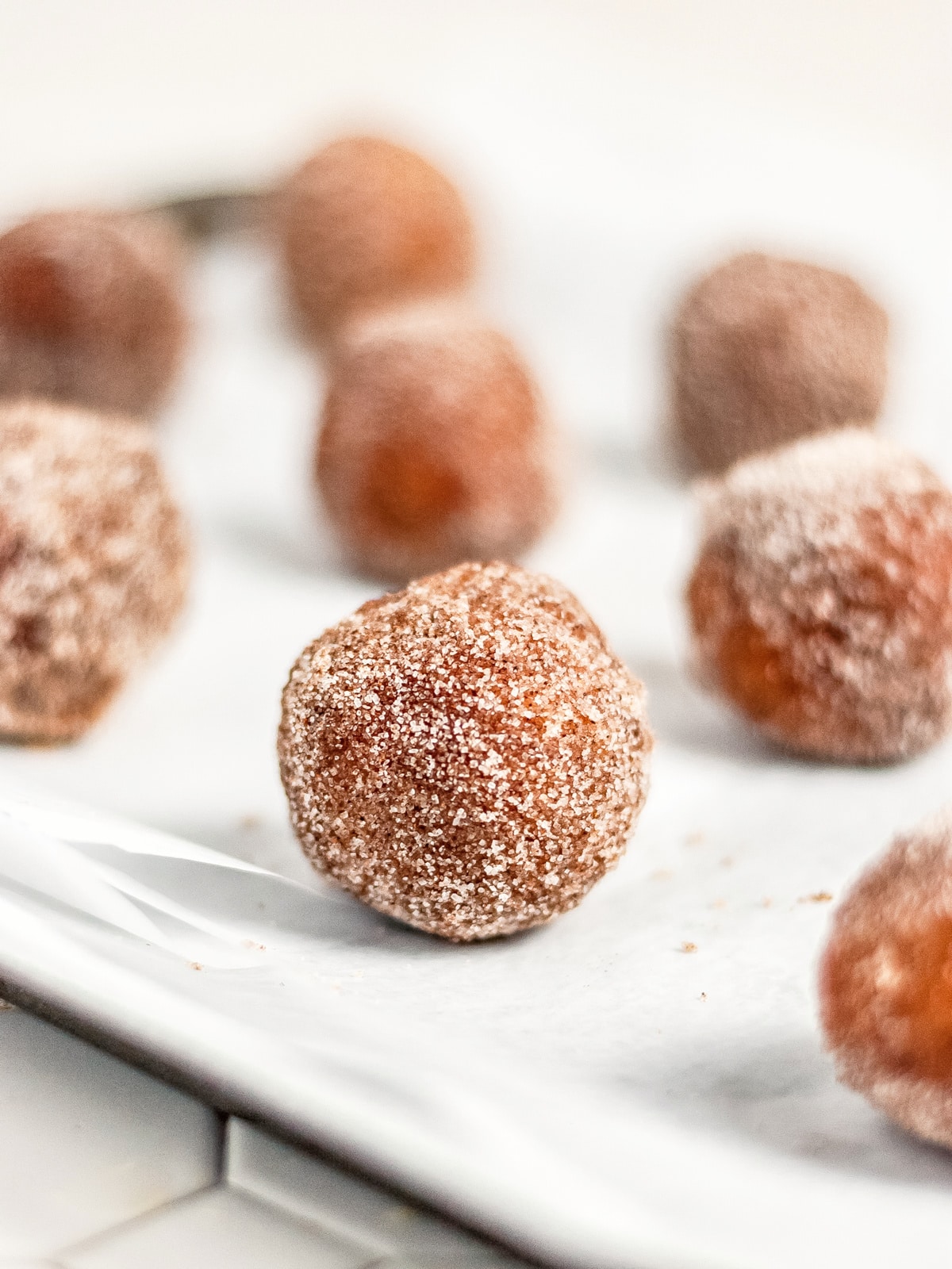 Coated donut holes dry on a plate.