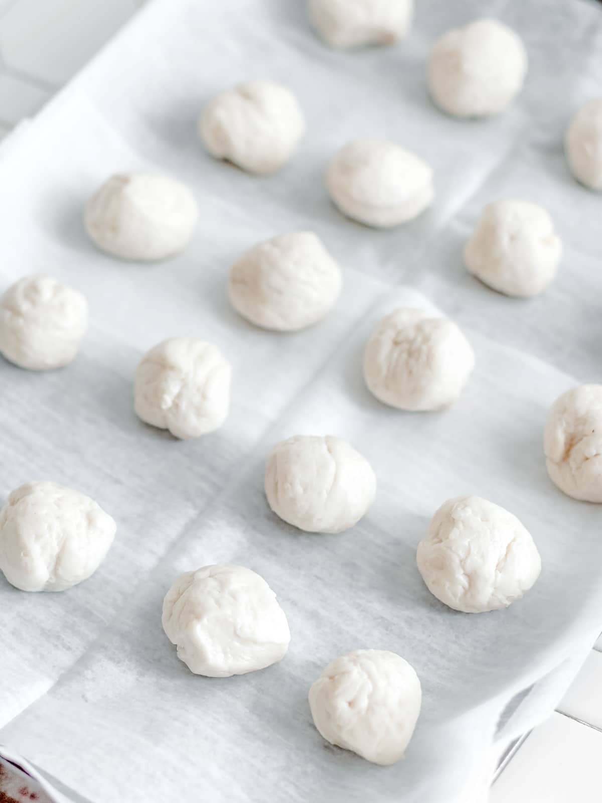 Biscuit pieces rolled into balls and placed on parchment paper.