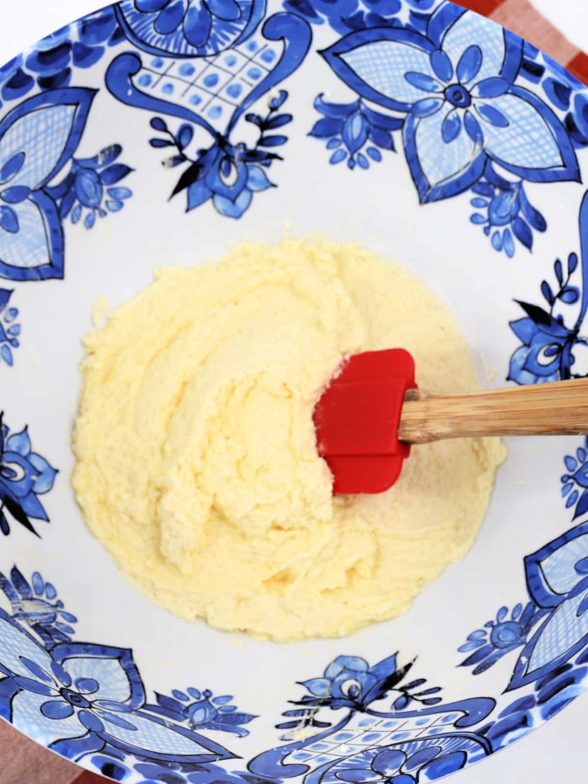A blue and white bowl with a red spatula in it.