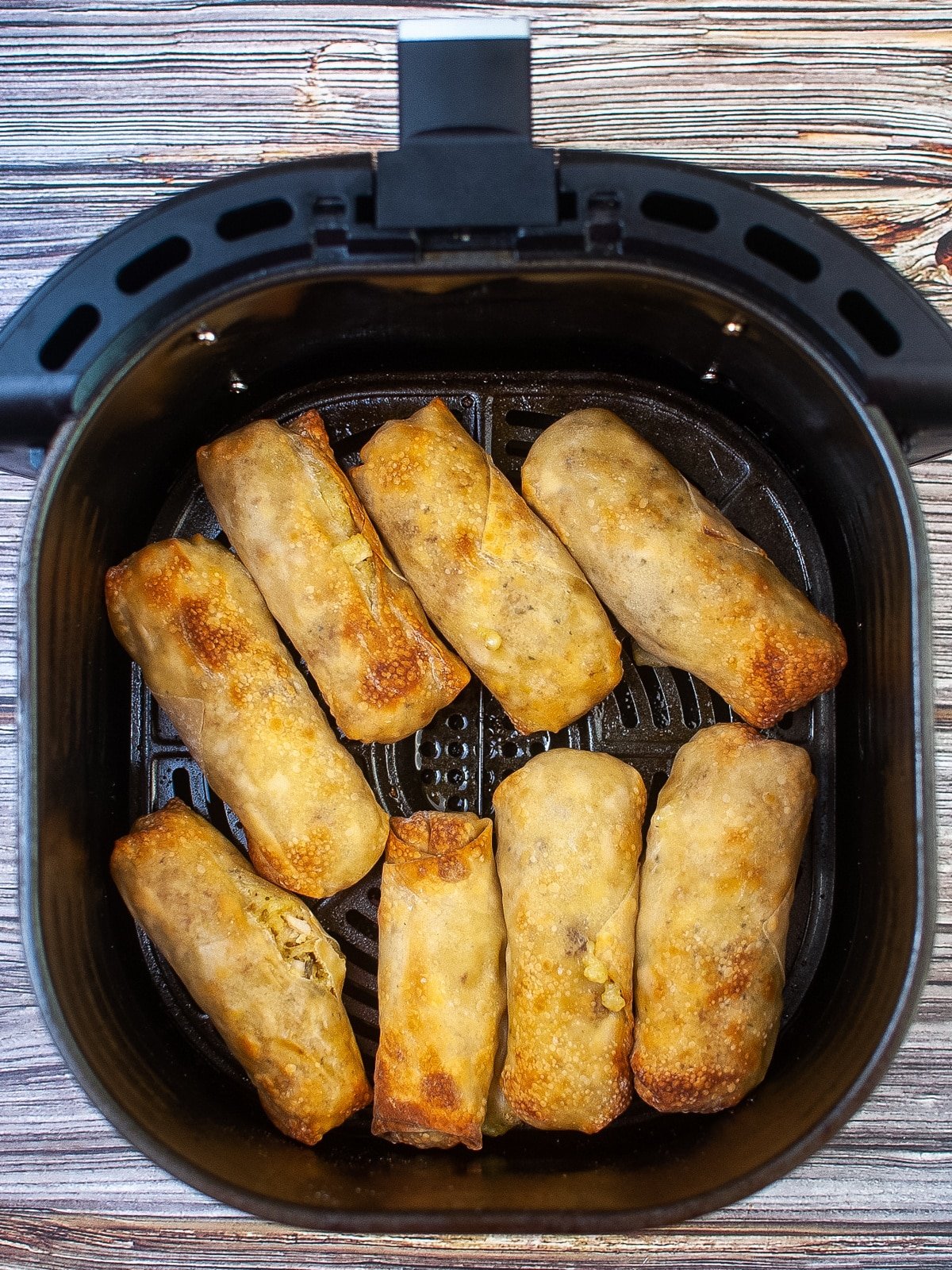 An air fryer filled with fried rolls.