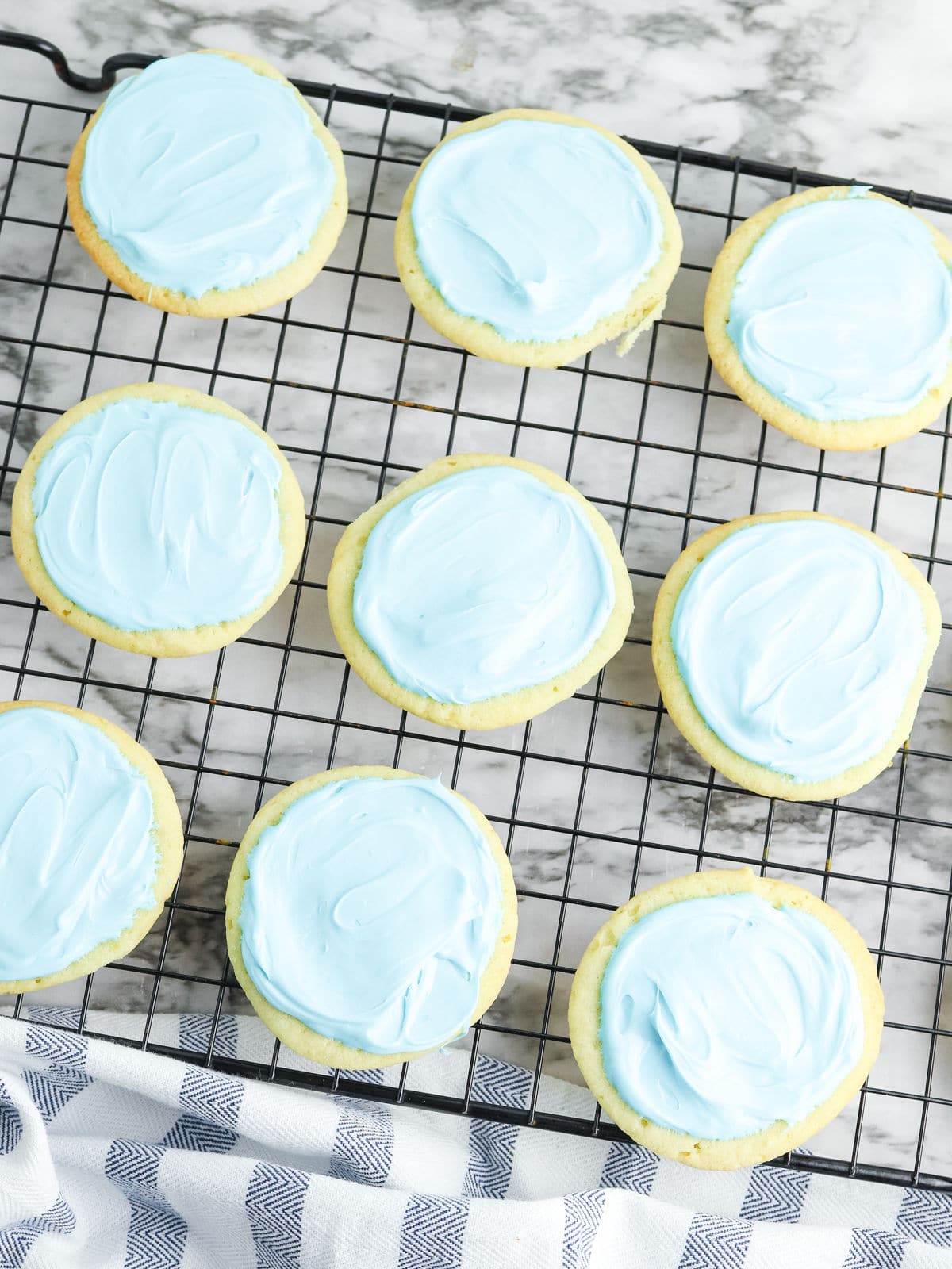 Cookies with blue icing on a cooling rack.