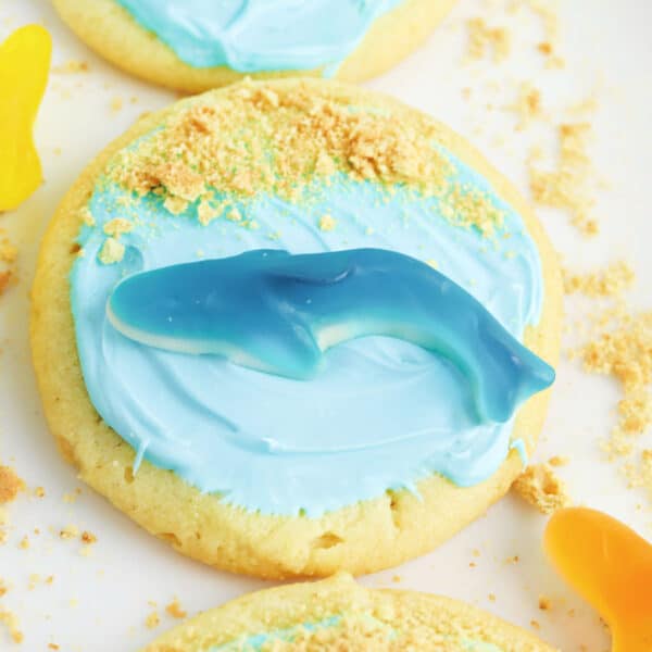 A group of cookies decorated with icing and graham cracker crumbs with a gummy shark.