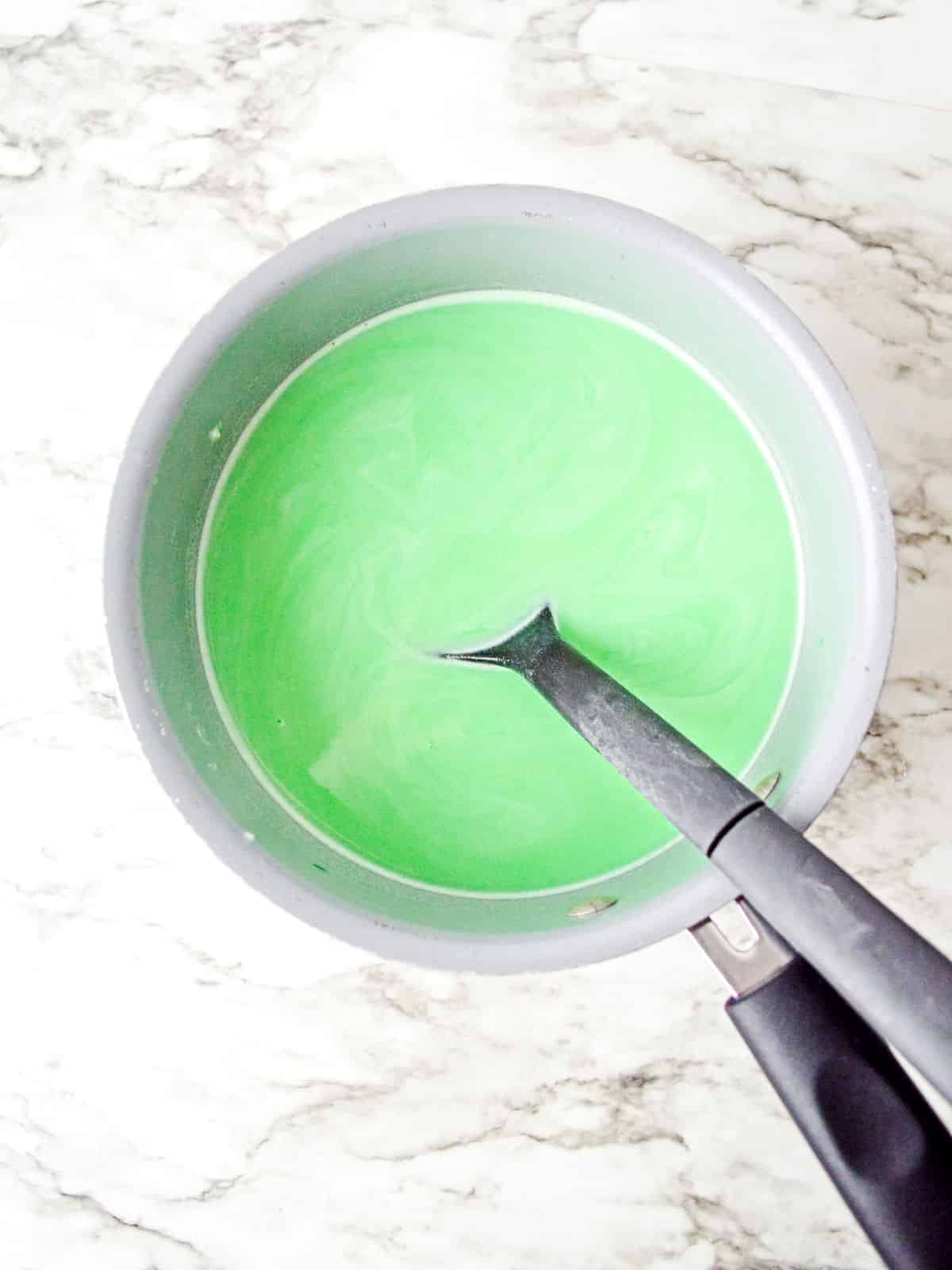 A green liquid in a pan with a spatula.