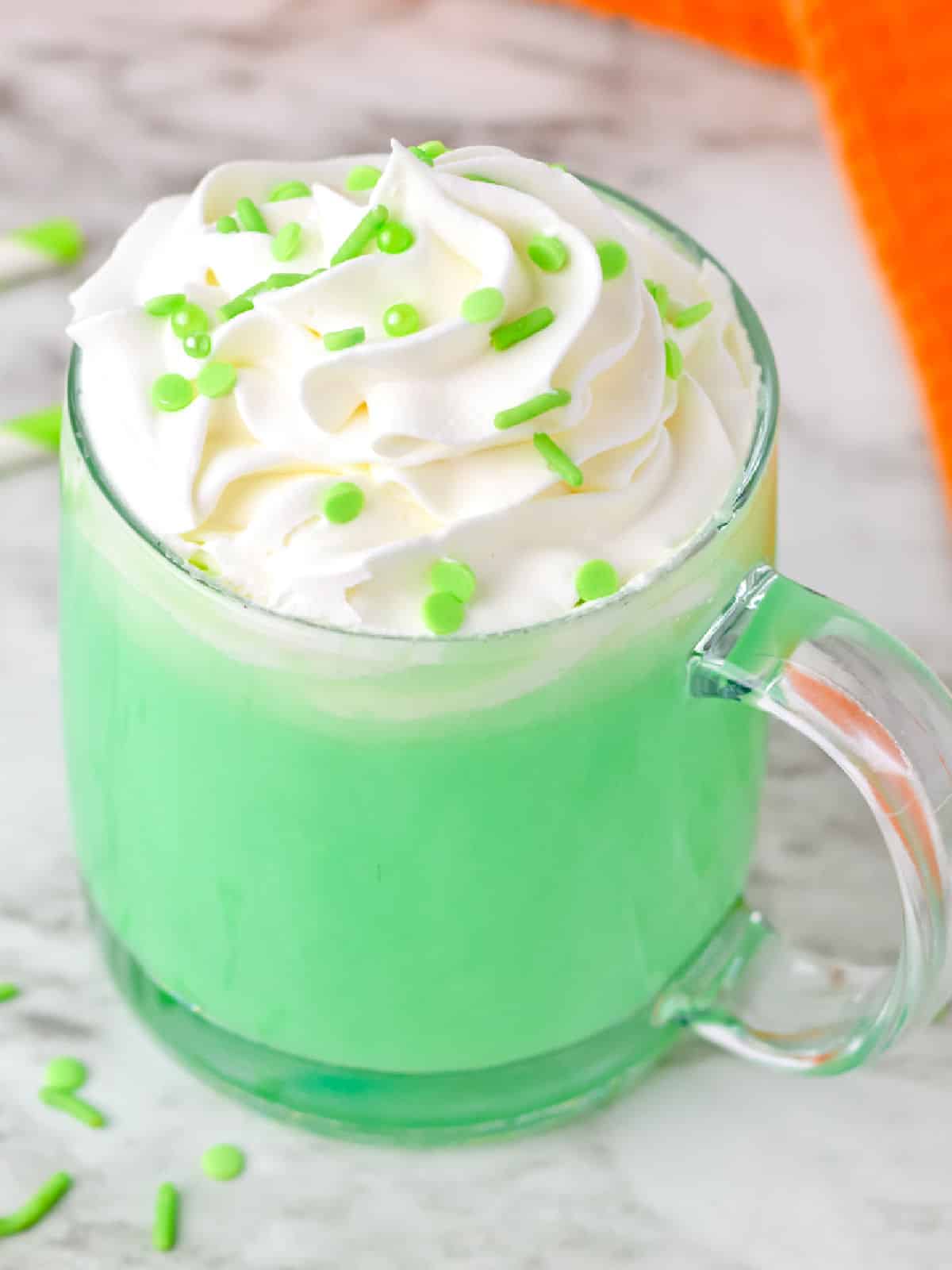 A green hot chocolate with whipped cream and sprinkles.