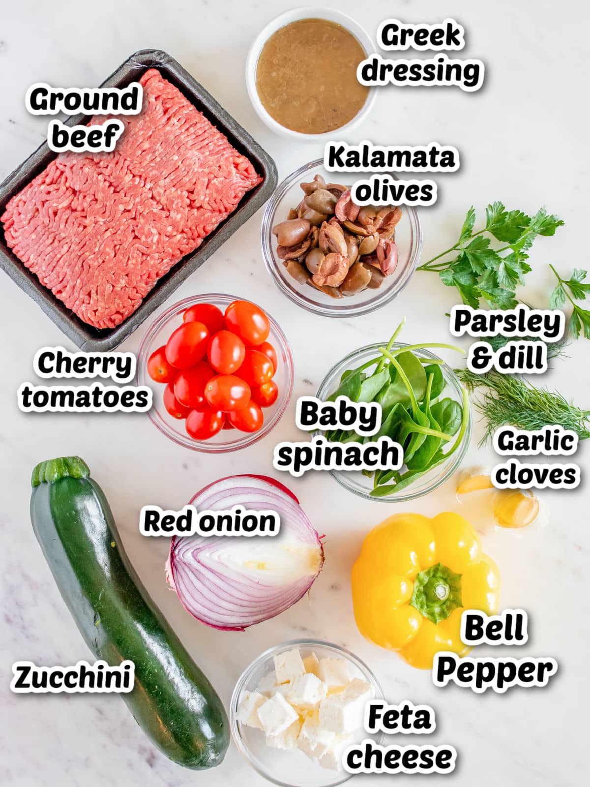 Various fresh ingredients for a greek salad with ground beef, labeled for identification.