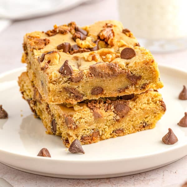 Stack of chocolate chip and nut blondies on a white plate.