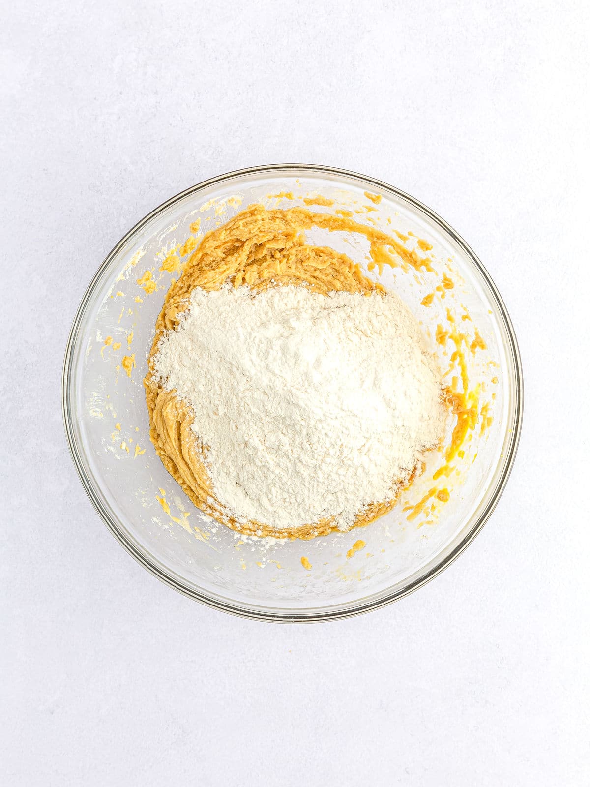 Mixing flour into batter in a glass bowl.