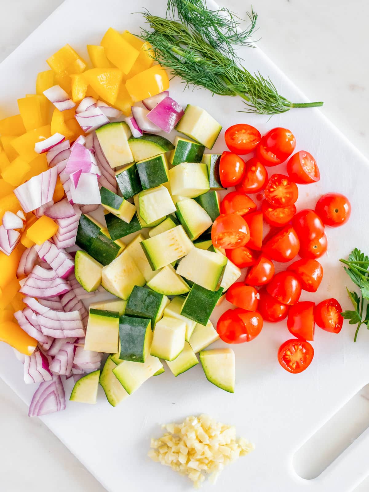 Assorted chopped vegetables on a cutting board, ready for cooking or salad preparation.