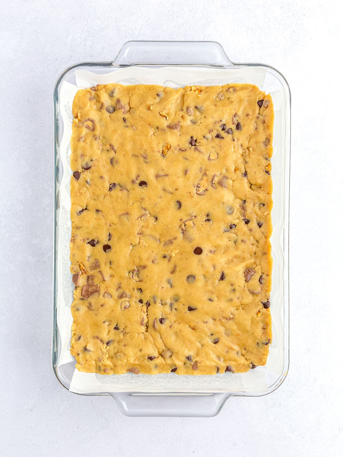 A tray of unbaked cookie dough with chocolate chips, ready to be baked.