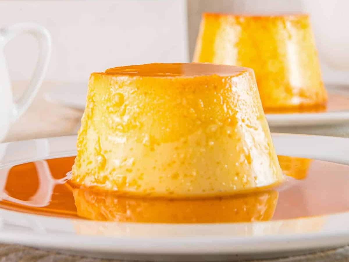 A close-up photo of a creamy flan with caramel sauce on a white plate.