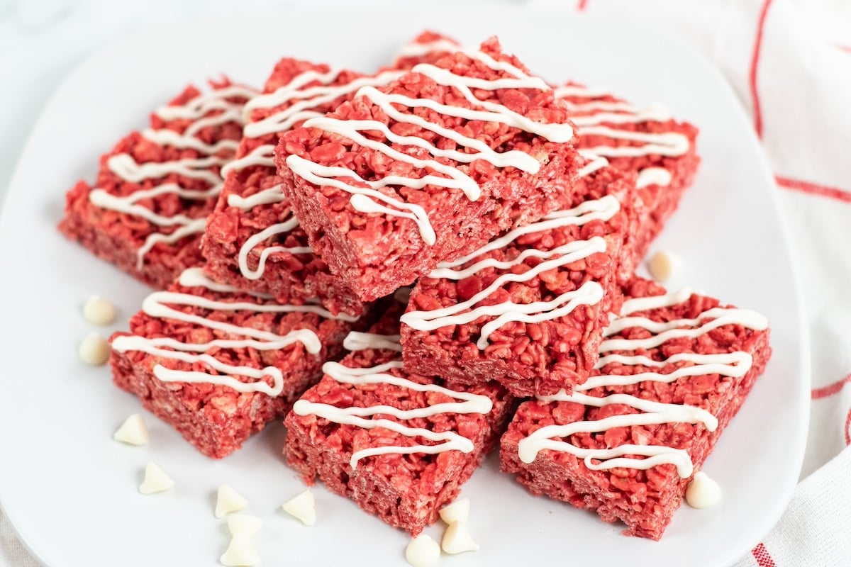 A plate of red velvet rice krispie treats drizzled with white icing.