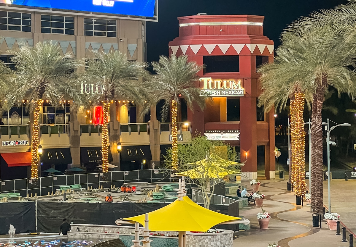 Outdoor night scene featuring Tulum Modern Mexican restaurant with illuminated palm trees and seating area in the foreground.