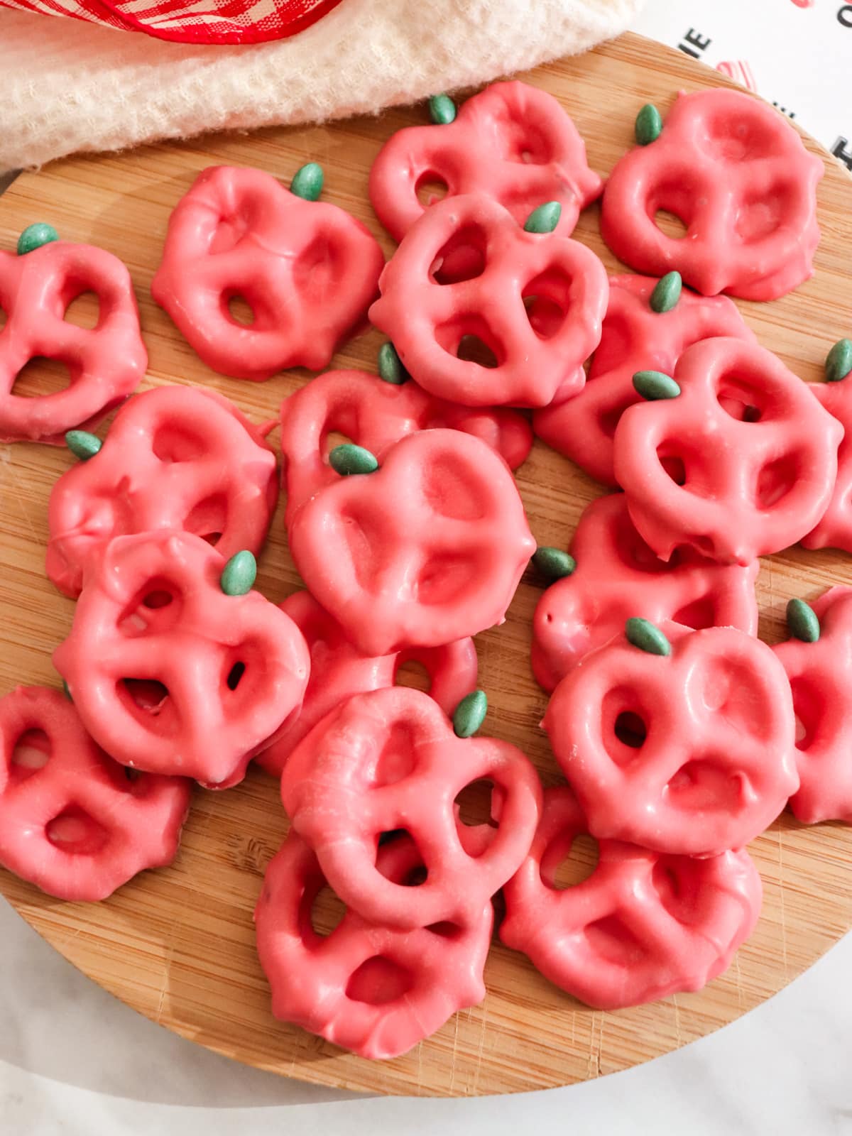 A wooden surface displaying a collection of pink pretzels with small green accents resembling leaves, arranged in a visually appealing manner.