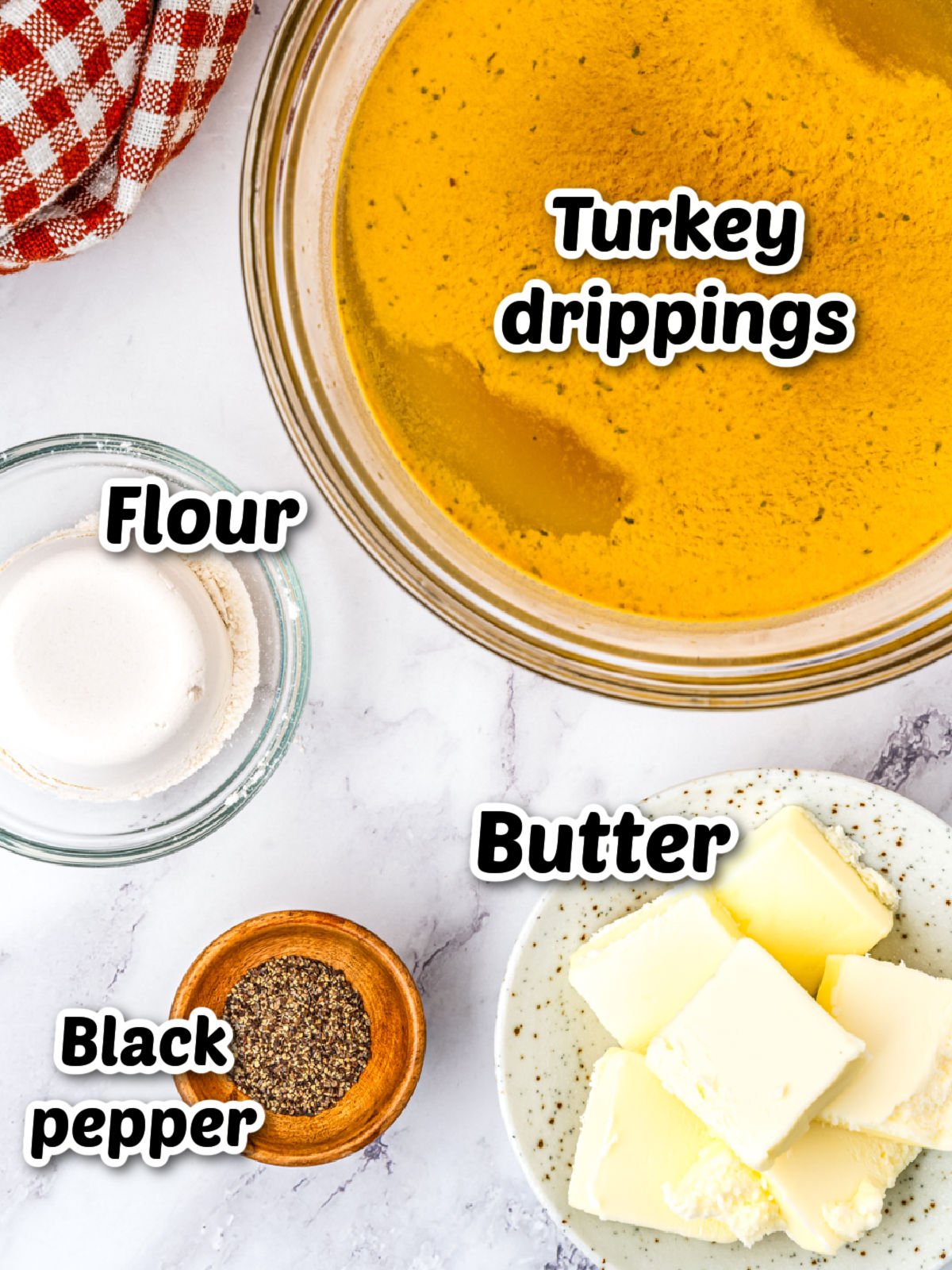 Ingredients on a countertop: a bowl of turkey drippings, a dish with butter cubes, a small bowl of black pepper, and a small glass bowl containing flour.