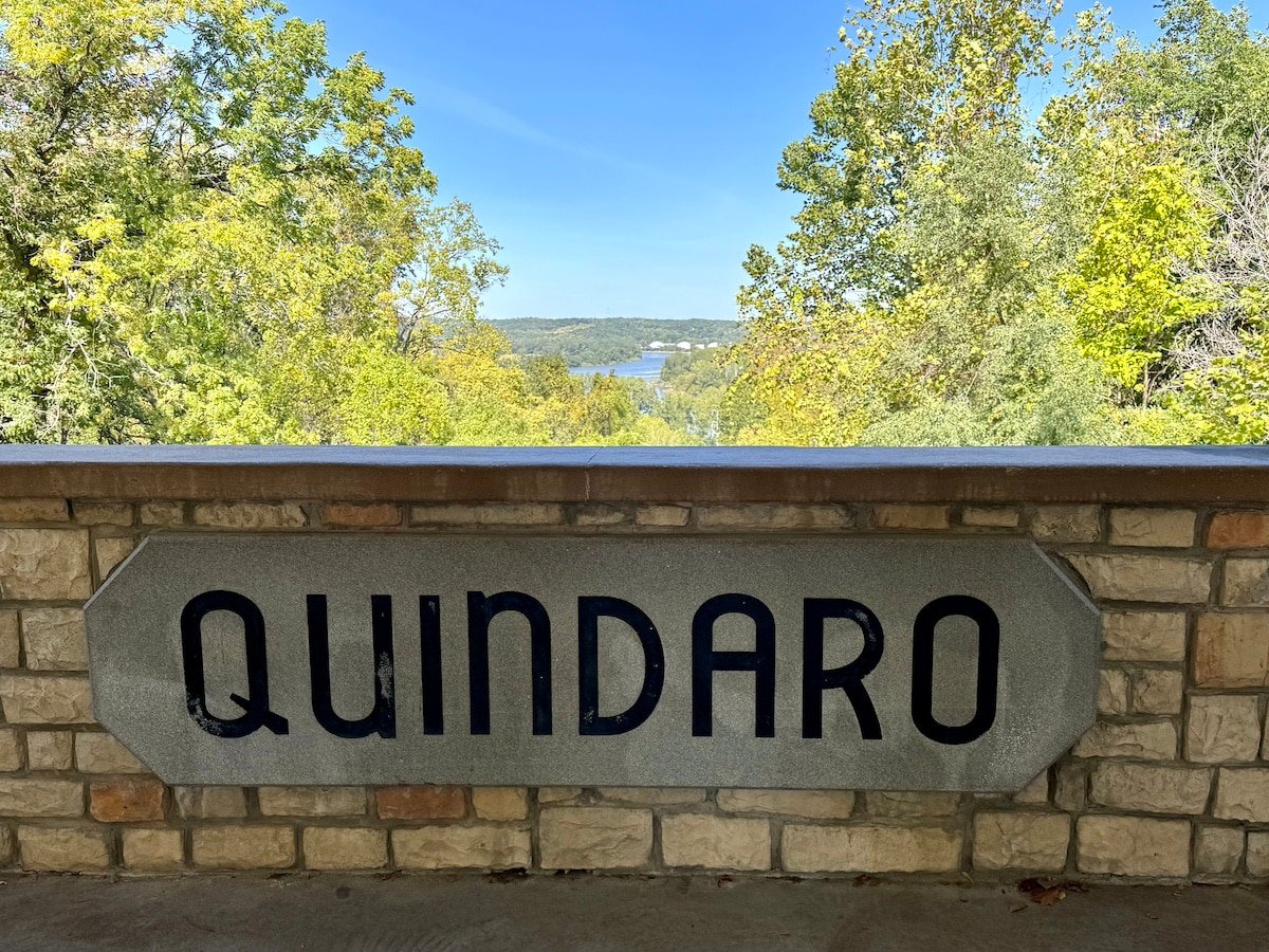 Stone sign reading "Quindaro" with trees and a river visible in the background.