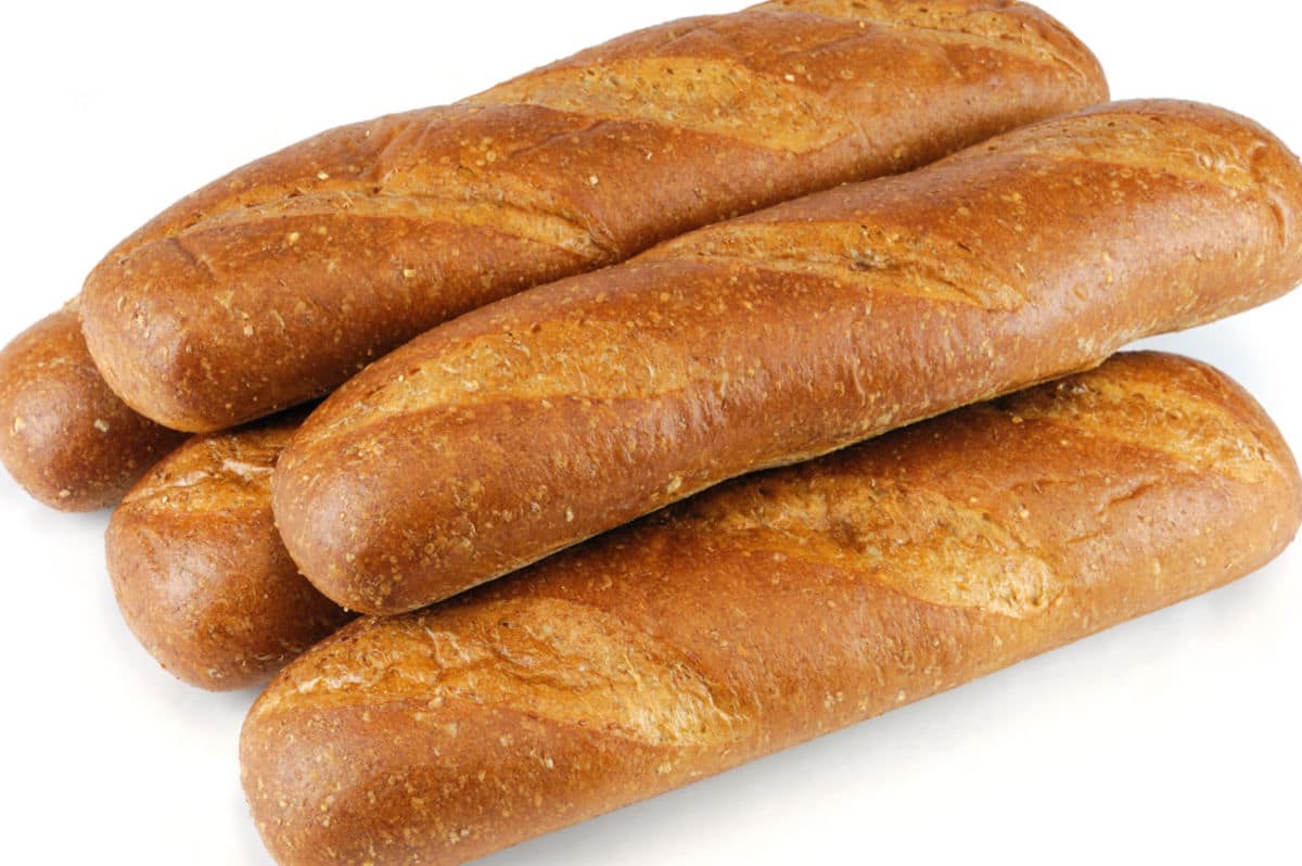 Four long, crusty baguettes stacked together on a white background.