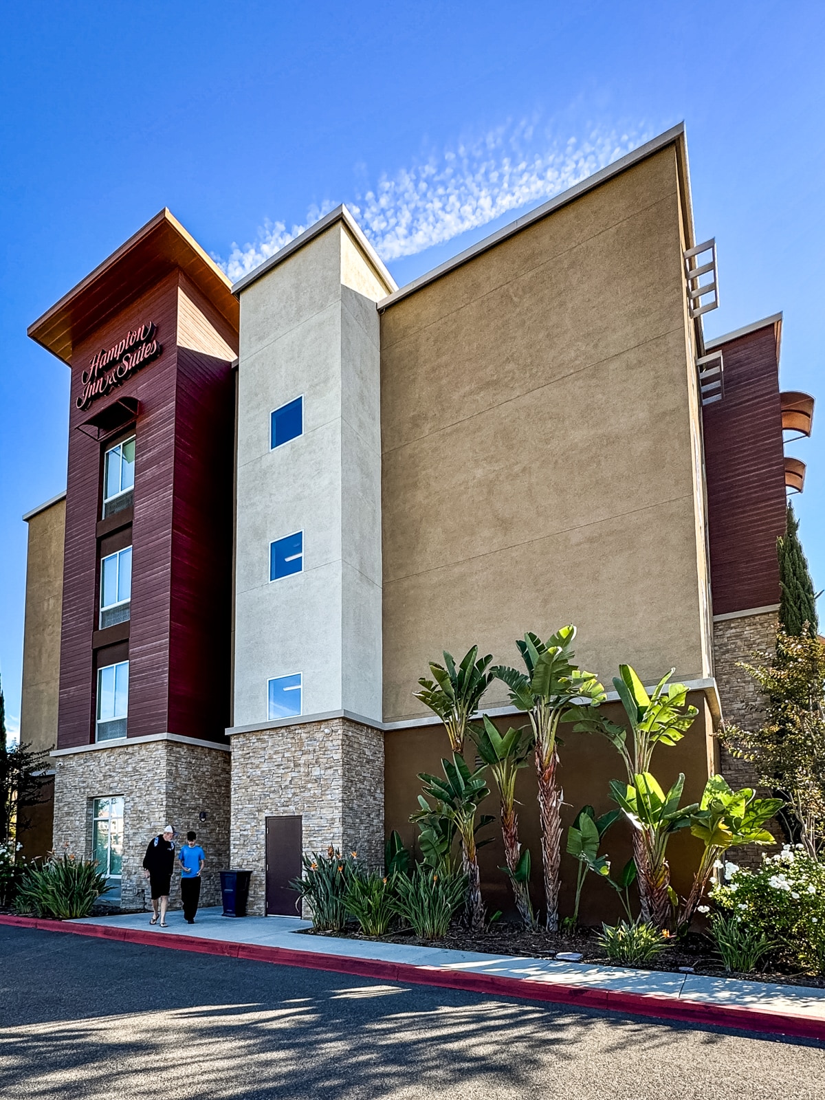 A building with palm trees and people walking in front of it.