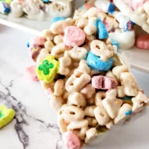 A close-up of a cereal treat bar made with marshmallows and colorful cereal pieces, placed on a marble surface.