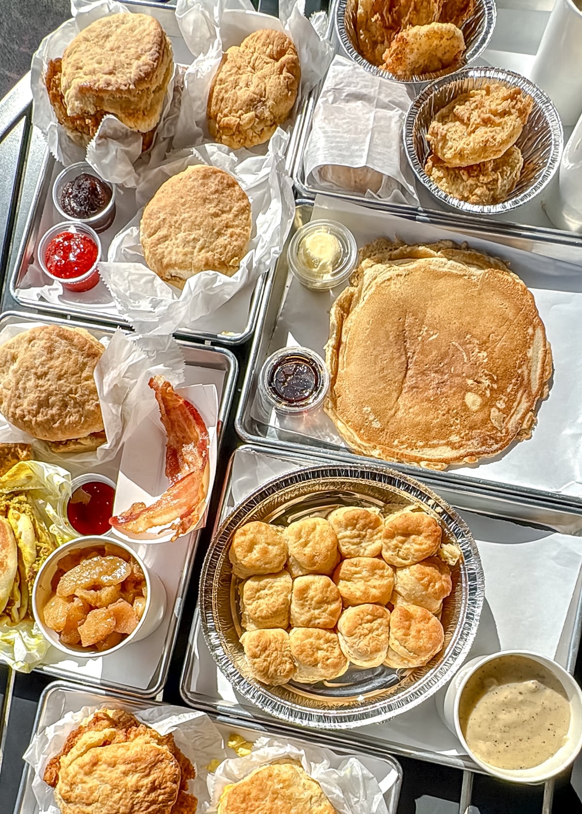 A variety of breakfast foods, including biscuits, pancakes, bacon, fried chicken, jam, and home fries, arranged on trays&mdash;perfect fuel before exploring the best Things to Do in Roanoke VA.