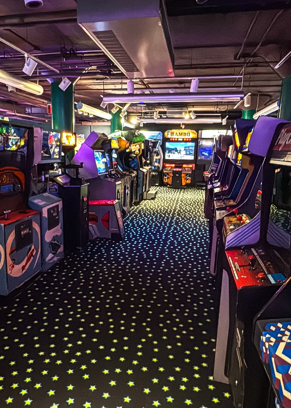 A dimly lit arcade filled with various retro arcade game machines and patterned carpet with star designs&mdash;one of the nostalgic things to do in Roanoke VA for gamers and families alike.